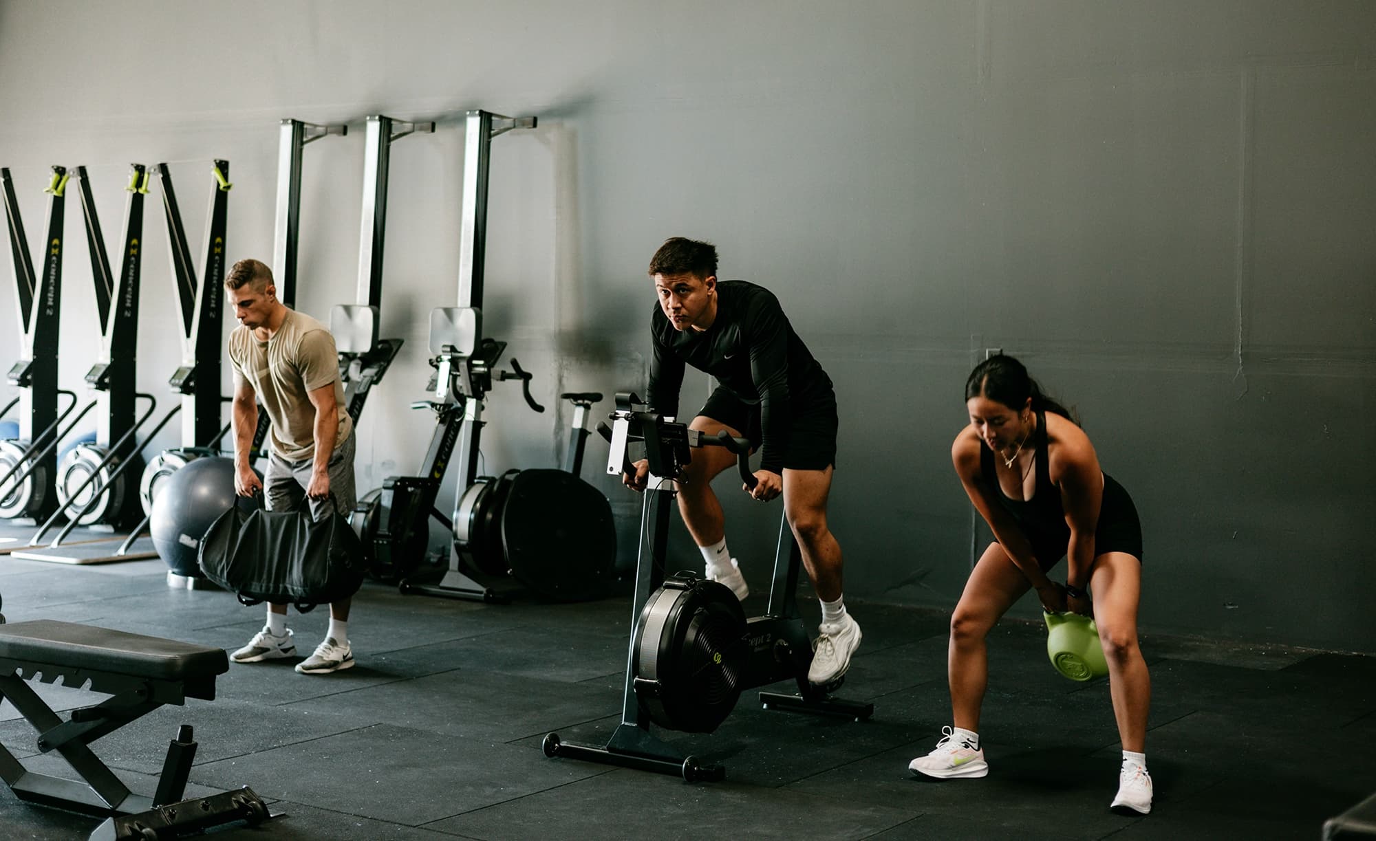 Peak Fitness trainer helps female member with upper body exercise