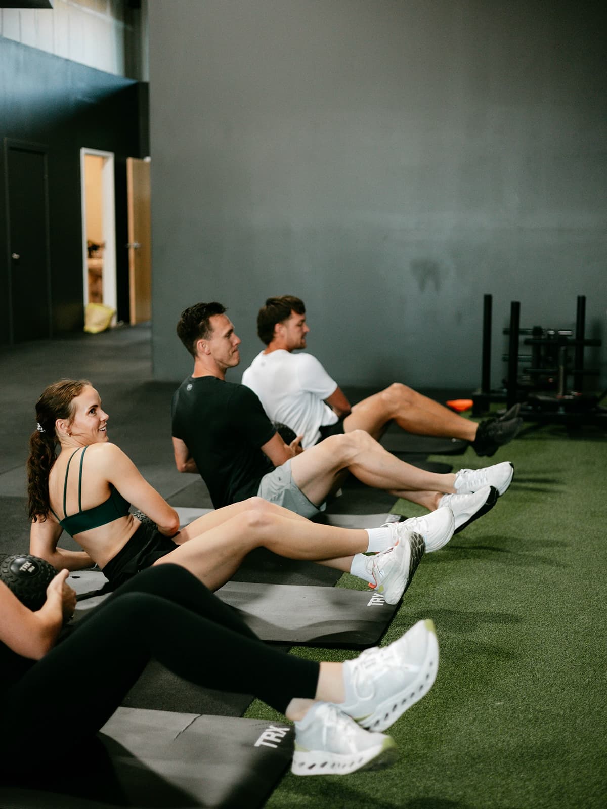 Peak Fitness trainer helps female member with upper body exercise